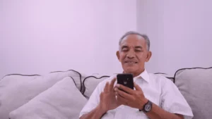 An elderly Indian woman learning to use a smartphone guided by her grandchild, showing Samarth Eldercare's approach to helping elders adopt technology