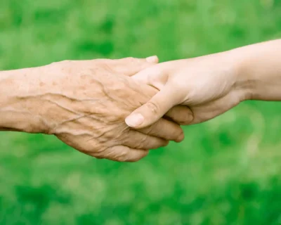 An elderly Indian man and woman sitting together on a sunlit veranda, smiling warmly — a Samarth Eldercare guide to the stages of old age and graceful ageing