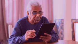 A friendly assistive robot interacting with a smiling elderly person in a care home, as Samarth Eldercare explores the role of robots in senior care