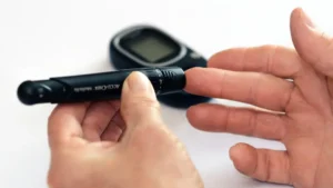 Elderly parent in India checking blood sugar with family support for diabetes management