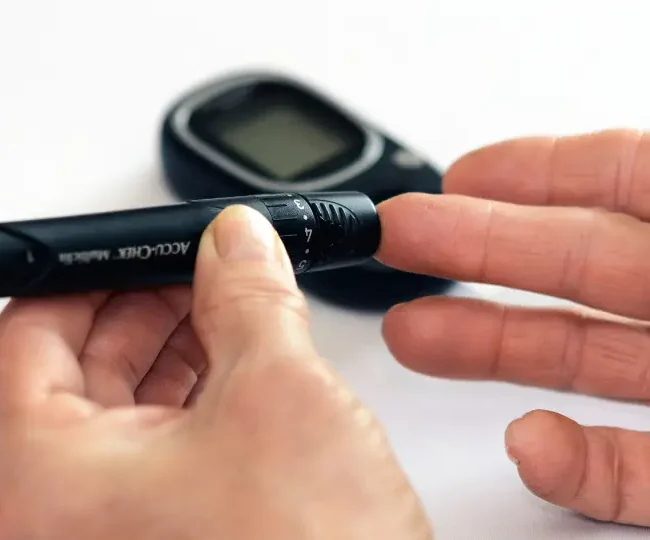 Elderly parent in India checking blood sugar with family support for diabetes management